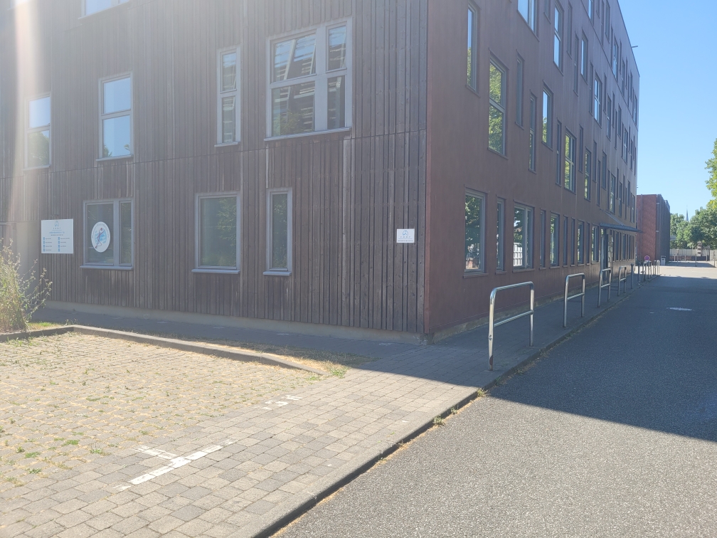 Angle du bâtiment 3 vu depuis le parking du cabinet, façade en bardage bois et arceaux à vélos le long du trottoir