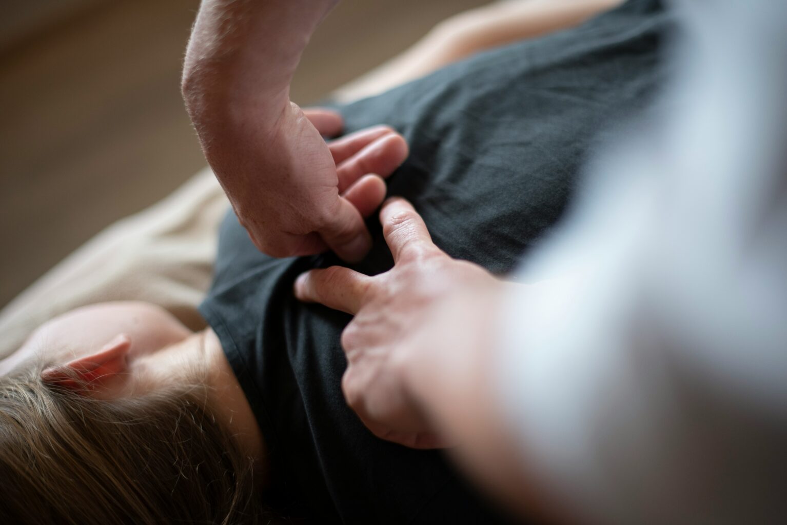 Travail tissulaire sur le haut du thorax, gros plan sur les mains de l'ostéopathe