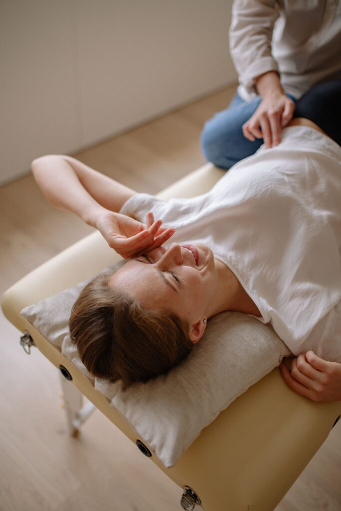 Patiente allongée sur une table de soin pendant une séance, bras au-dessus de la tête