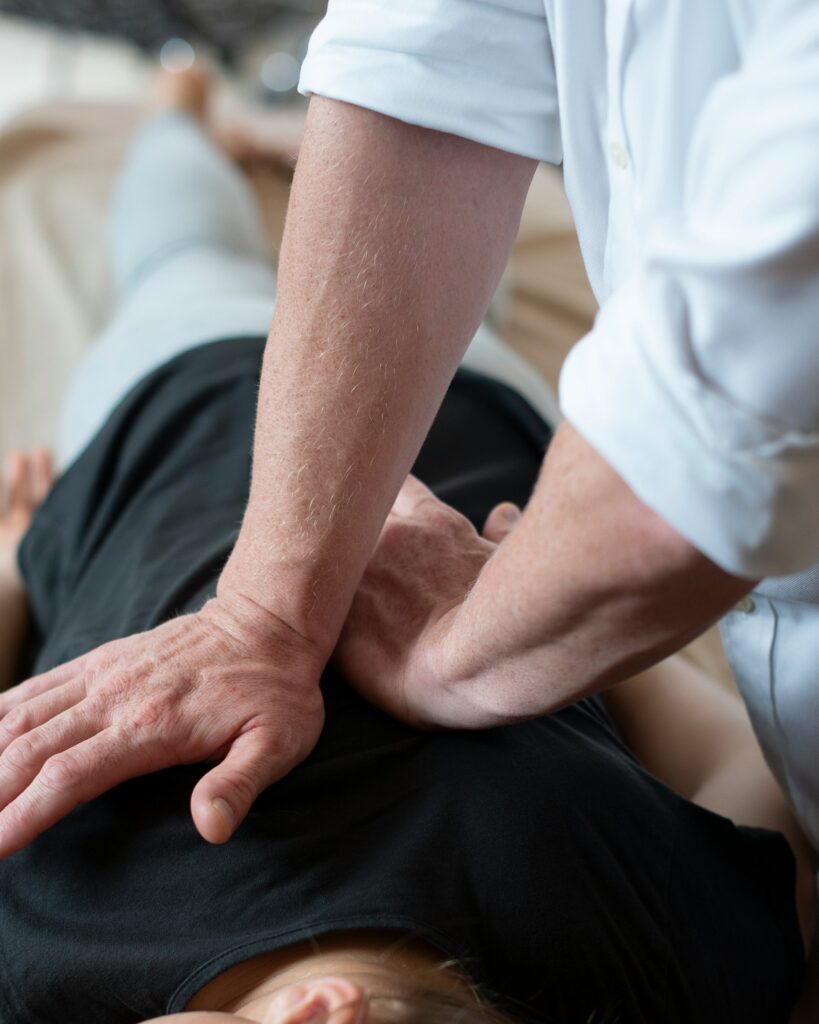 Mains d'un ostéopathe en appui sur le haut du dos d'un patient allongé sur le ventre